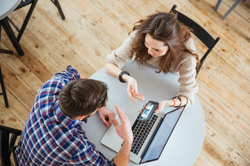 Poster - Couple sitting and looking at mobile phone screen in cafe