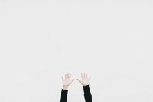 Two Hands Raised Against A White Wall
