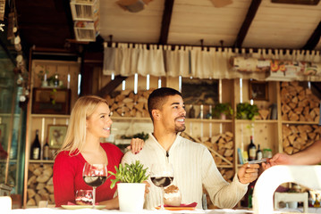 Multiracial couple paying bill at restaurant.