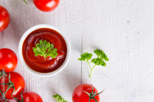 Fotografía Bowl of tomato sauce and cherry tomatoes on wooden table.