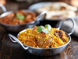 Wall Mural - balti dish with indian chicken biryani and curry in the background