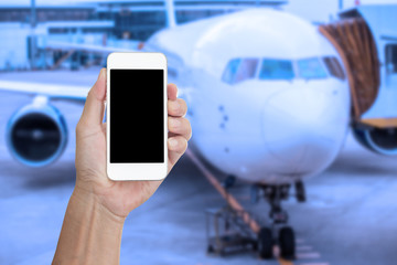 Hand holding mobile phone with blank screen and blur airplane ba