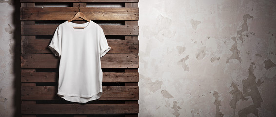 photo white tshirt hanging in front of concrete wall. wide