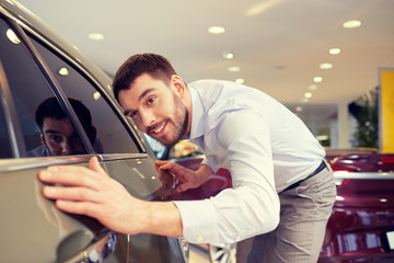 Wall Mural - happy man touching car in auto show or salon