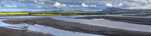 Panorama With River Banks And White Clouds In Iceland