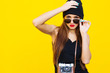 © zadorozhna - Close up fashion lifestyle portrait young hipster girl, wearing bright make up and  sunglasses, making sexy faces. Urban yellow  wall background.