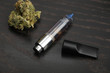 Cannabis oil dispenser/electronic cannabis oil vaporizer with oil-filled cartridge on wood surface