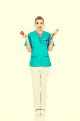 Shocked nurse or female doctor holding stethoscope and heart mod