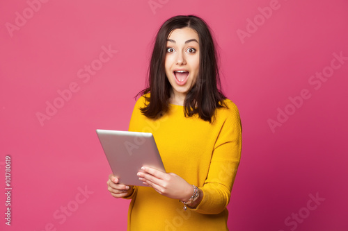Fotografía Surprised young woman holding tablet computer