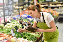 Supermarket Employee Putting Vegetables In Shelves