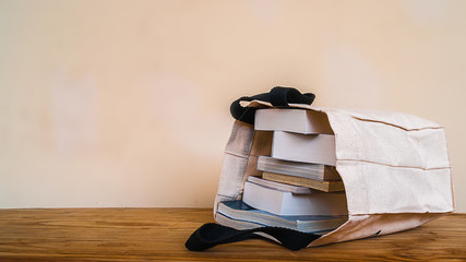 books inside cloth bag on wood table,vintage style.