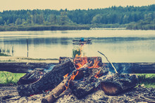 Rustic Bonfire By The Lake In The Forest On The Background Of Bl