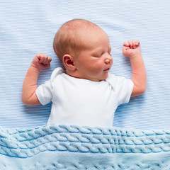 Newborn baby boy under a blue blanket