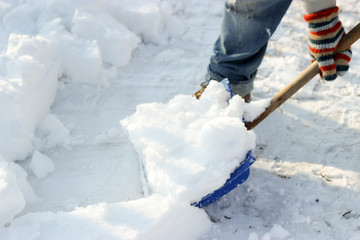 man cleans the track from snow shoveling, sunny winter day