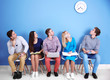© Africa Studio - Young people sitting on a chairs and looking at the clock in blue hall