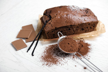 Wall Mural - Chocolate cake with cocoa powder, vanilla pods on white table