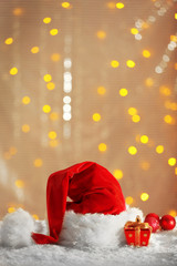 Wall Mural - Santa Claus red hat with Christmas decorations on the artificial snow against shiny background, close up