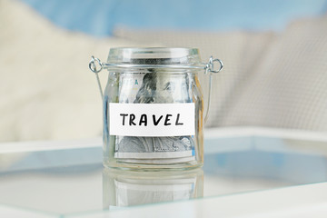 Poster - Glass jar with dollar banknotes for travel on a table