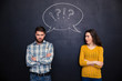 © Drobot Dean - Frowning couple standing after argument over chalkboard background