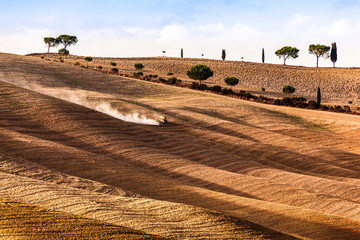 Wall Mural - Tuscany fields autumn landscape, Italy. Harvest season, tractor working