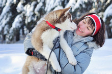 Cheerful Woman Having Fun With Her Little Cute Siberian Husky Puppy In Winter Forest Full Of Snow. Lifestyle Concept