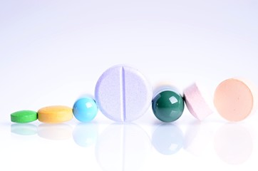     Tablets isolated on a white background. Reflection of pills on a glass. Medicine´s background. Pharmacy. Close up of capsules. 