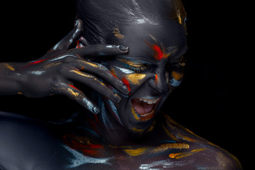 Portrait of a young woman who is posing covered with  black paint 