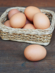 Wall Mural - eggs in a basket wooden background