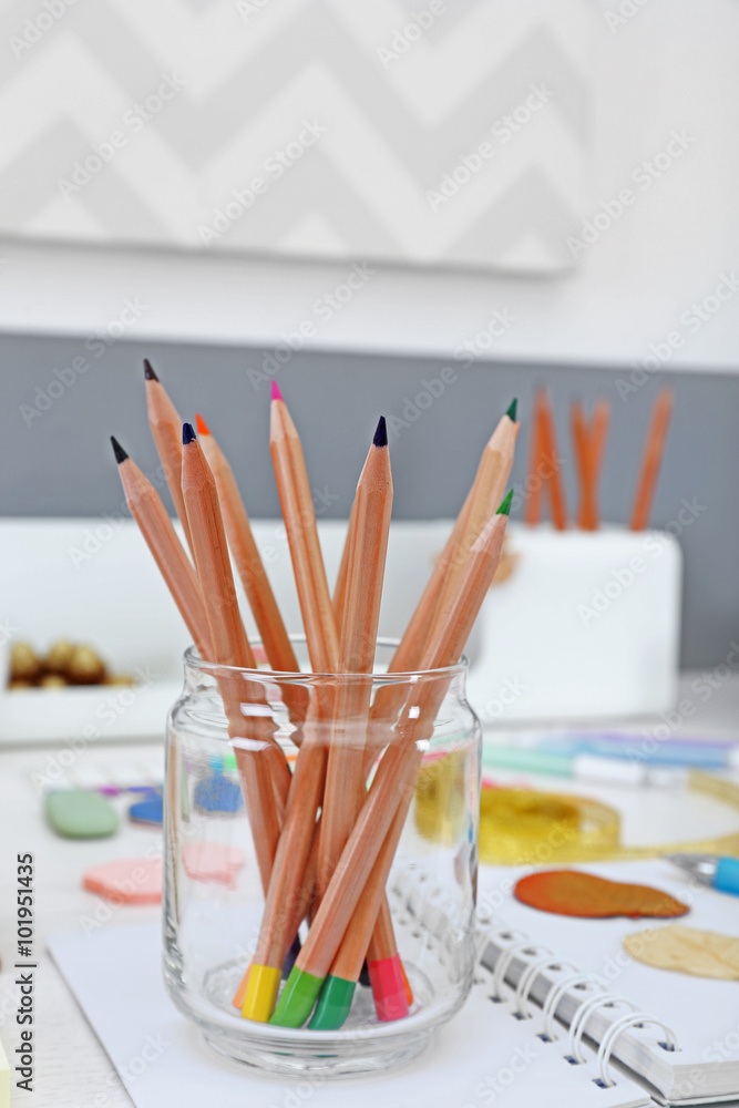 Set of coloured pencils in glass jar on a table