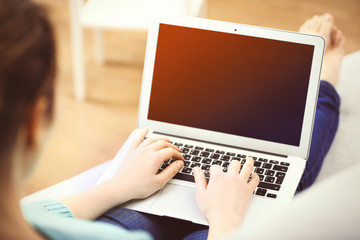 Canvas Print - Woman sitting on sofa with a laptop in a room