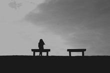 The Silhouette Of Woman Sitting Alone With Grey Sky, Concept Of Lonely, Sad, Alone, Person Space