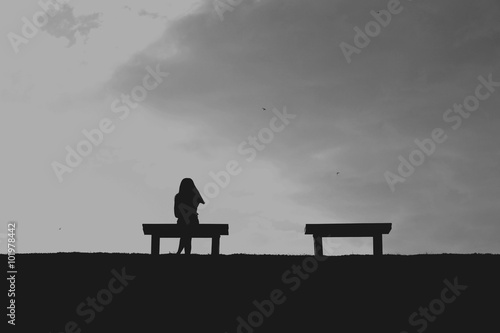 La silhouette de femme assise seule avec ciel gris, concept de solitaire, triste Poster