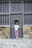 Fototapeta Na drzwi - Niña mirando a través de puerta de madera antigua