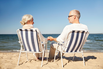 Canvas Print - happy senior couple in chairs on summer beach