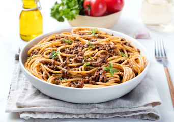 Spaghetti bolognese with cheese and basil on a plate Italian ingredients background