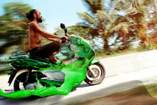 Yoga Biker Fast Rides A Green Inks Splashed Motorcycle,tropic Blur Background