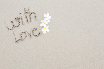 The word with love wth white flowers on the beach surface backgr