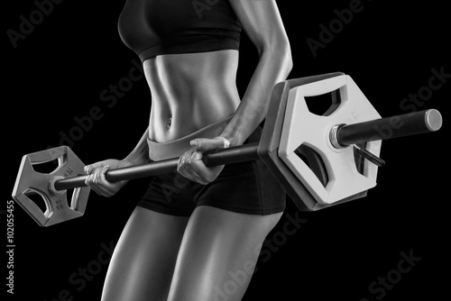 Plakat na zamówienie Young woman exercises with barbell isolated over black backgroun