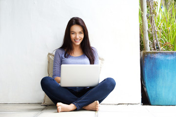 Wall Mural - Happy young woman sitting on floor with a laptop