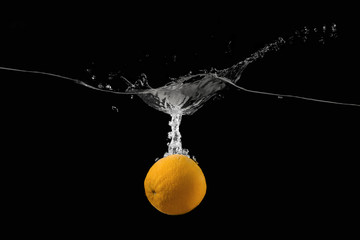 Orange falling into the water on a dark background