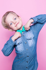 Wall Mural - Young beautiful boy with blue shirt and butterfly tie. Studio portrait over pink background