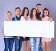 © shefkate - Happy young group of people standing together and holding a blank