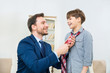 © zinkevych - Young businessman helping smiling son to knot tie