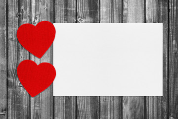 Red hearts and blank paper on black and white wooden background