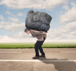 businessman holding a big rock on a road