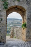 Fototapeta Uliczki - City gate in Monteriggioni with view on Tuscan countryside