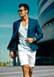 © halayalex - High fashion look.Young stylish confident happy handsome  businessman model man in blue suit cloth lifestyle in the street in sunglasses behind sky