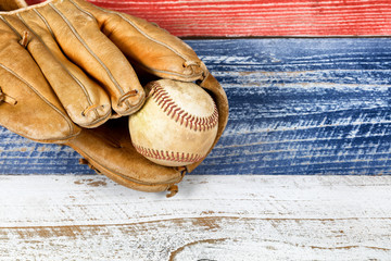 worn baseball mitt and ball on faded boards painted in USA colors