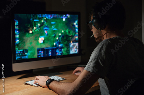 Concentrated gamer in headphones using computer for playing game Canvas Print