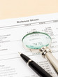 © wirojsid - Balance sheet financial report with pen, and magnifier; document